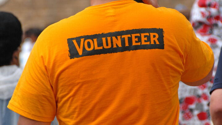 A volunteer wearing an orange VOLUNTEER shirt at a sports event