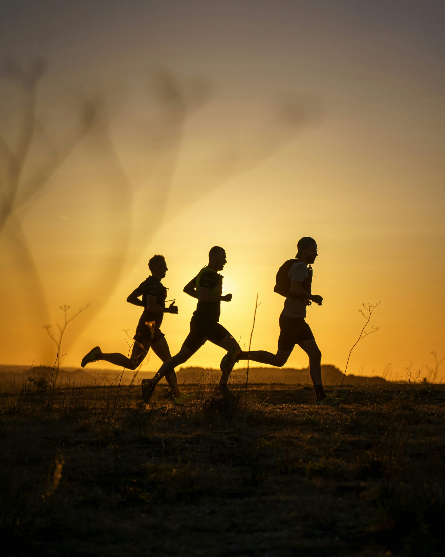 Drie lopers in silhouet op een pad bij zonsondergang